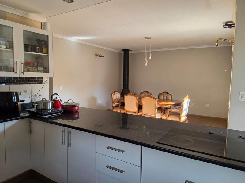 Open-plan kitchen and dining area featuring granite countertops, modern cabinetry, and a central freestanding fireplace, creating a functional and connected living space.