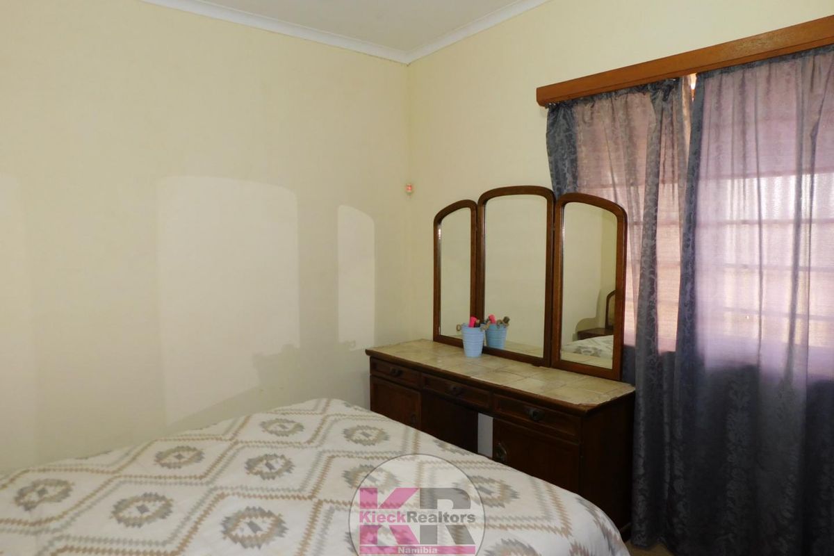 A standard bedroom featuring neutral wall finishes and a window with curtain track.