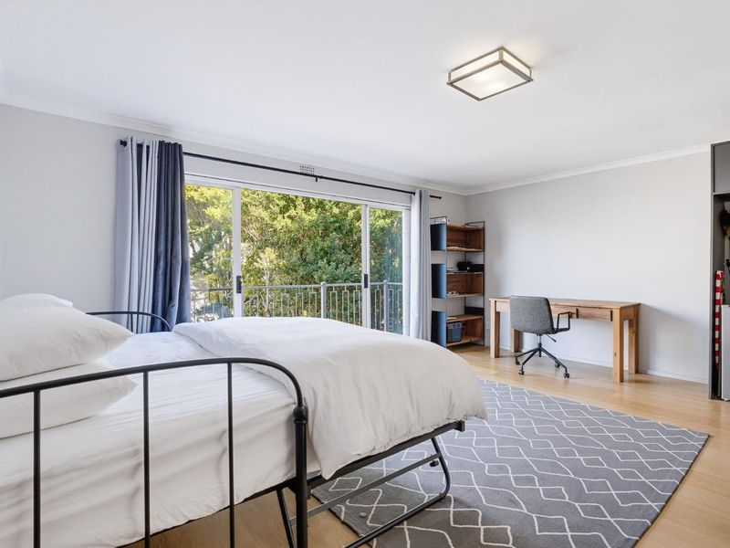Spacious bedroom featuring light laminate flooring, a ceiling light fixture, and a large sliding glass door providing access to a private balcony.