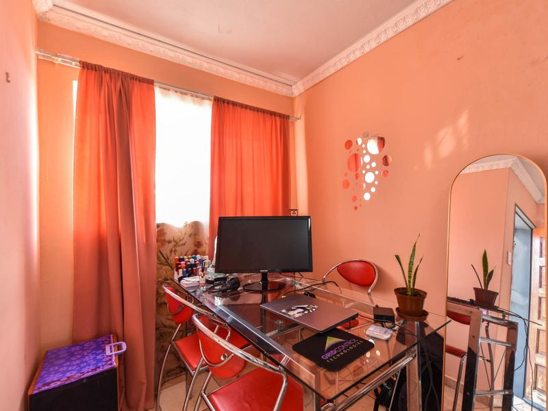 A compact home office space featuring decorative ceiling cornicing and natural light, currently utilized as a workspace.