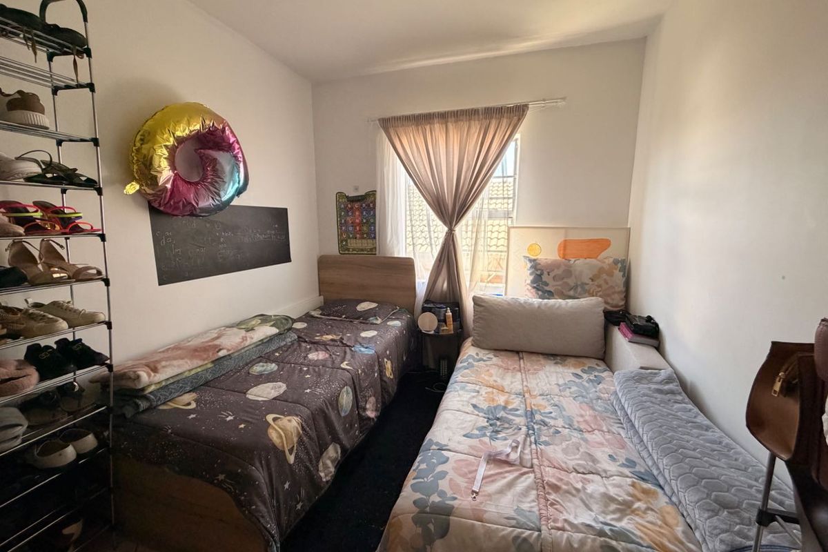 A compact bedroom featuring a window with natural light, suitable for a twin or single occupancy layout.