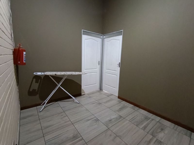 A functional utility space featuring tiled flooring and two internal doors, suitable for storage or laundry use.