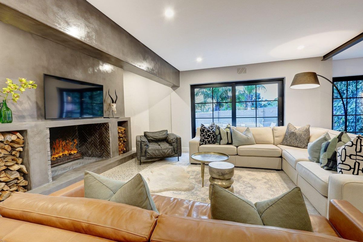 Modern living room featuring a striking concrete fireplace with integrated log storage, terrazzo flooring, and large black-framed sliding doors opening to the outdoors.