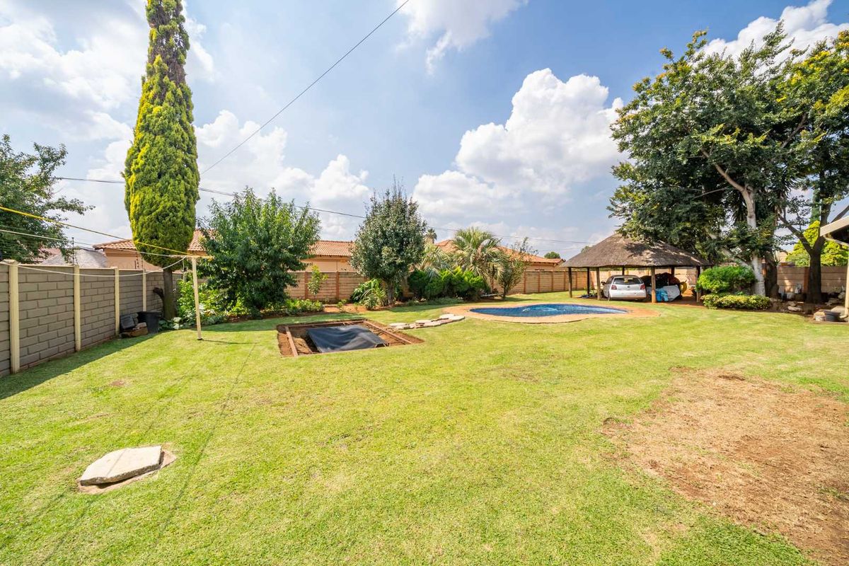 Spacious rear garden featuring a swimming pool, a thatched lapa, and perimeter walling, offering potential for outdoor landscaping and entertainment.