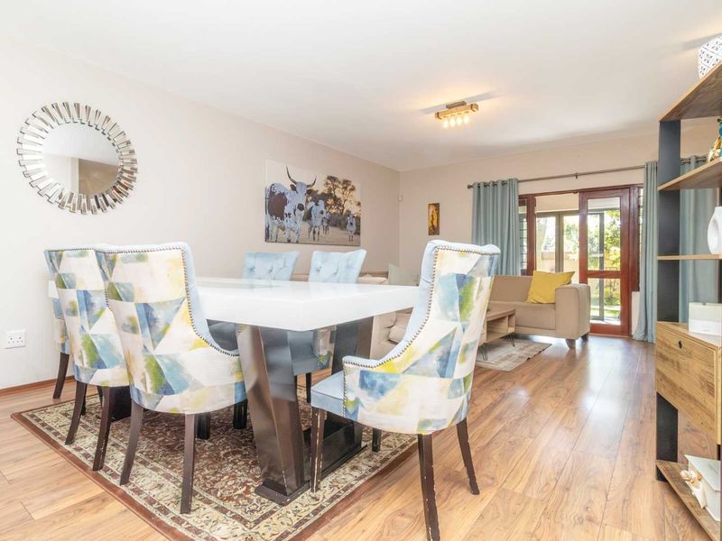 An open-plan living and dining area featuring laminate flooring, neutral walls, and a sliding glass door providing access to the outdoor space.
