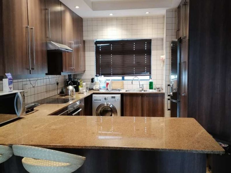 Modern kitchen featuring dark wood cabinetry, granite countertops, integrated appliances, and recessed lighting, offering a functional and stylish workspace.