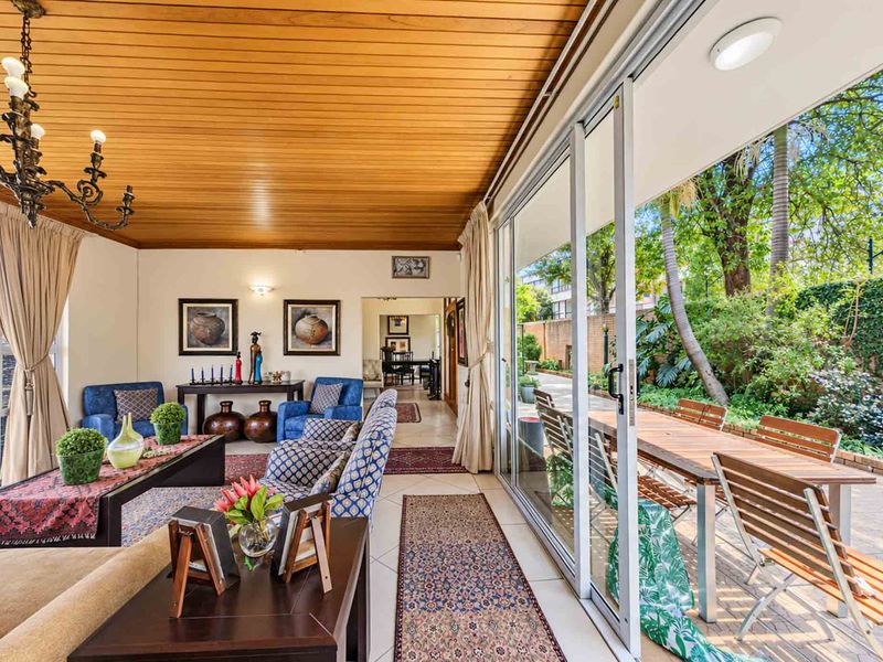 A spacious covered patio featuring a warm timber ceiling, tiled flooring, and large sliding glass doors that provide seamless access to the garden area.