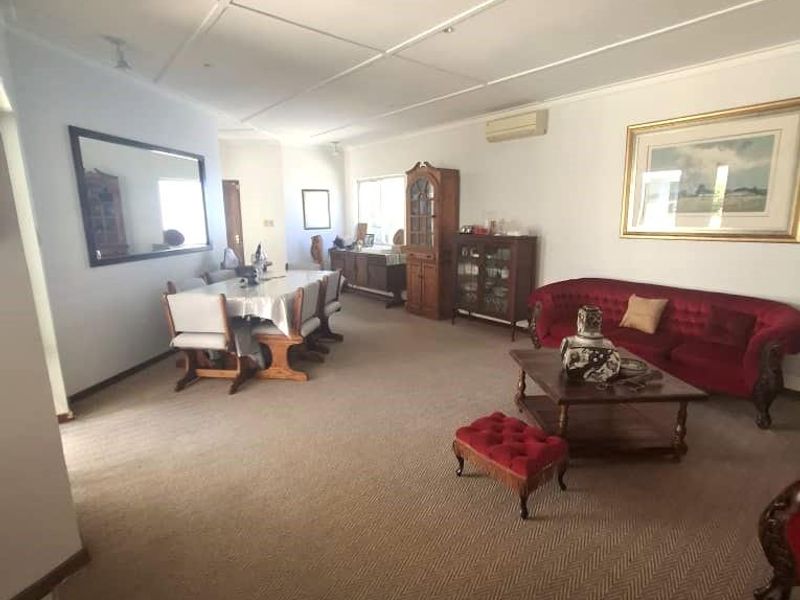 Spacious open-plan living and dining area featuring carpeted flooring and a split-system air conditioner.