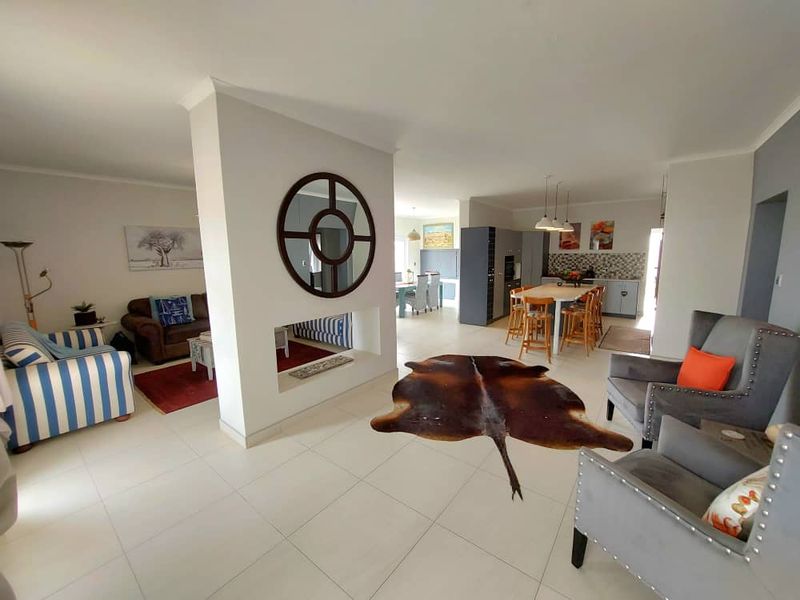 Spacious open-plan living area featuring a central fireplace partition, tiled flooring, and a modern kitchen with a breakfast island.