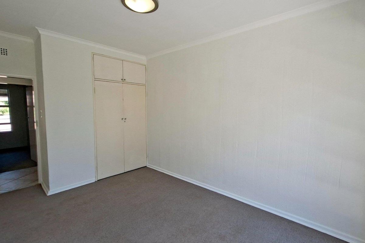 A vacant bedroom featuring neutral walls, carpeted flooring, and built-in storage cupboards.