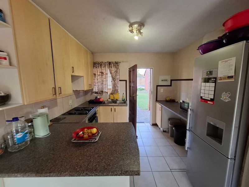 Functional kitchen featuring laminate cabinetry, built-in hob, tiled flooring, and direct access to the rear exterior area.