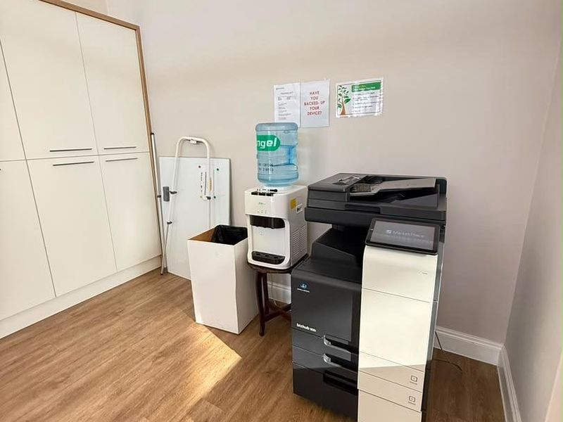 A functional office space featuring light wood-look laminate flooring and integrated floor-to-ceiling storage cabinetry.