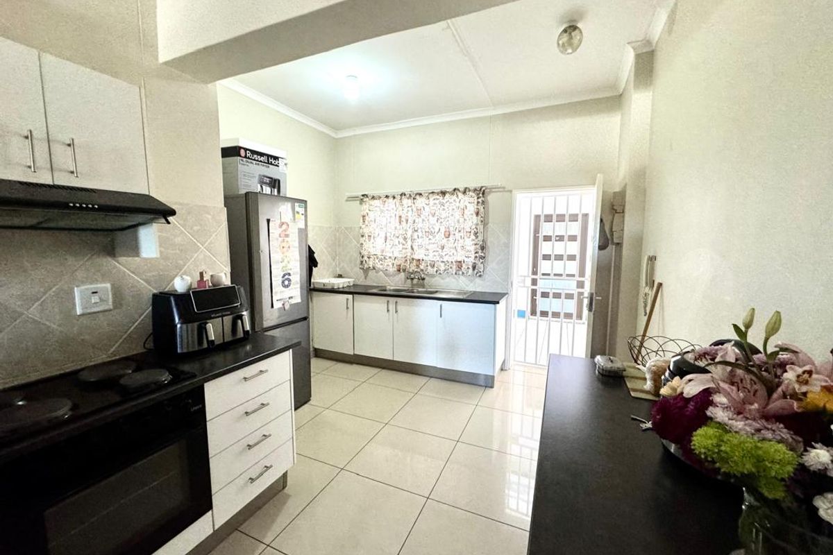 Functional kitchen featuring white cabinetry, dark countertops, built-in oven and stove, tiled flooring, and direct access to an exterior security gate.