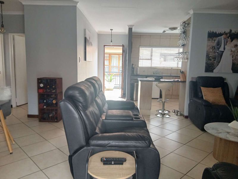 Open plan living area featuring tiled flooring and a breakfast bar kitchen layout, providing a functional and connected space for daily living.