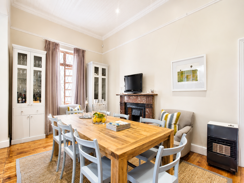 Elegant dining room featuring polished hardwood floors, a classic marble fireplace, and custom built-in cabinetry, offering a warm and sophisticated atmosphere.