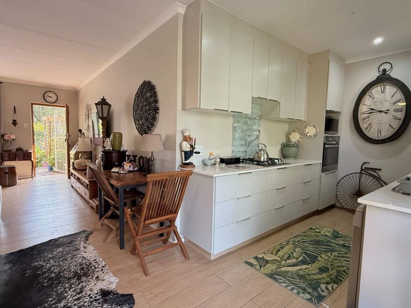 Open-plan living area featuring a modern kitchen with built-in cabinetry, gas hob, and oven, seamlessly flowing into the adjacent living space with outdoor access.