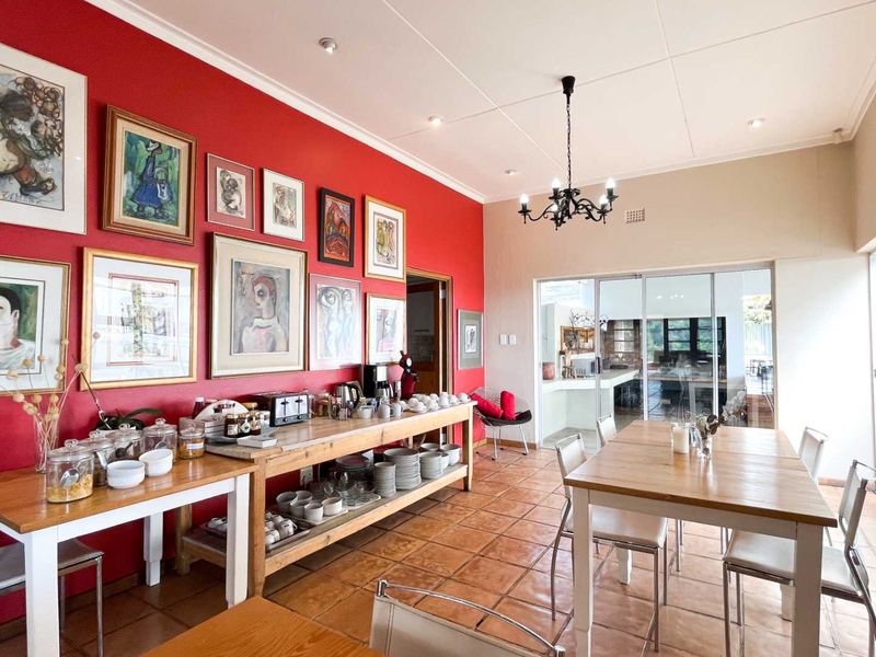 Spacious dining area featuring terracotta tiled flooring, a decorative wrought iron chandelier, and large sliding glass doors providing ample natural light.