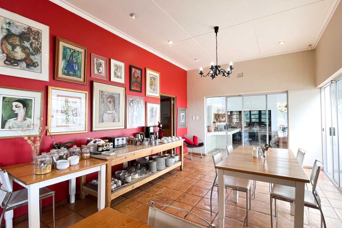 Spacious dining area featuring terracotta tiled flooring, a decorative wrought iron chandelier, and large sliding glass doors providing ample natural light.