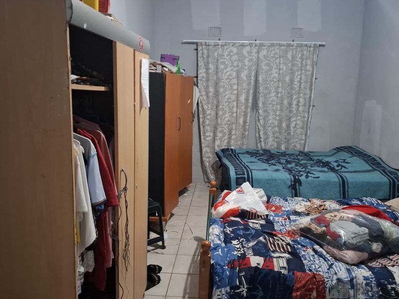 A bedroom featuring tiled flooring and wall-mounted curtain rods, currently requiring cosmetic attention to the walls and paint finishes.
