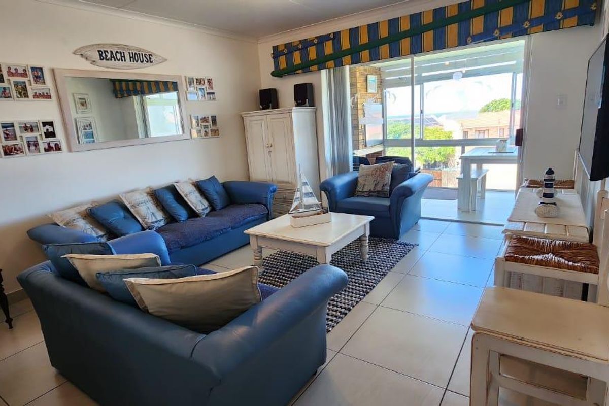 A bright living room featuring large sliding glass doors that open onto a balcony, with neutral floor tiles and ample natural light.