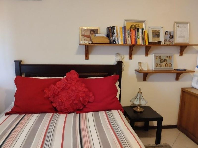 A bedroom featuring wall-mounted shelving units above the bed area.