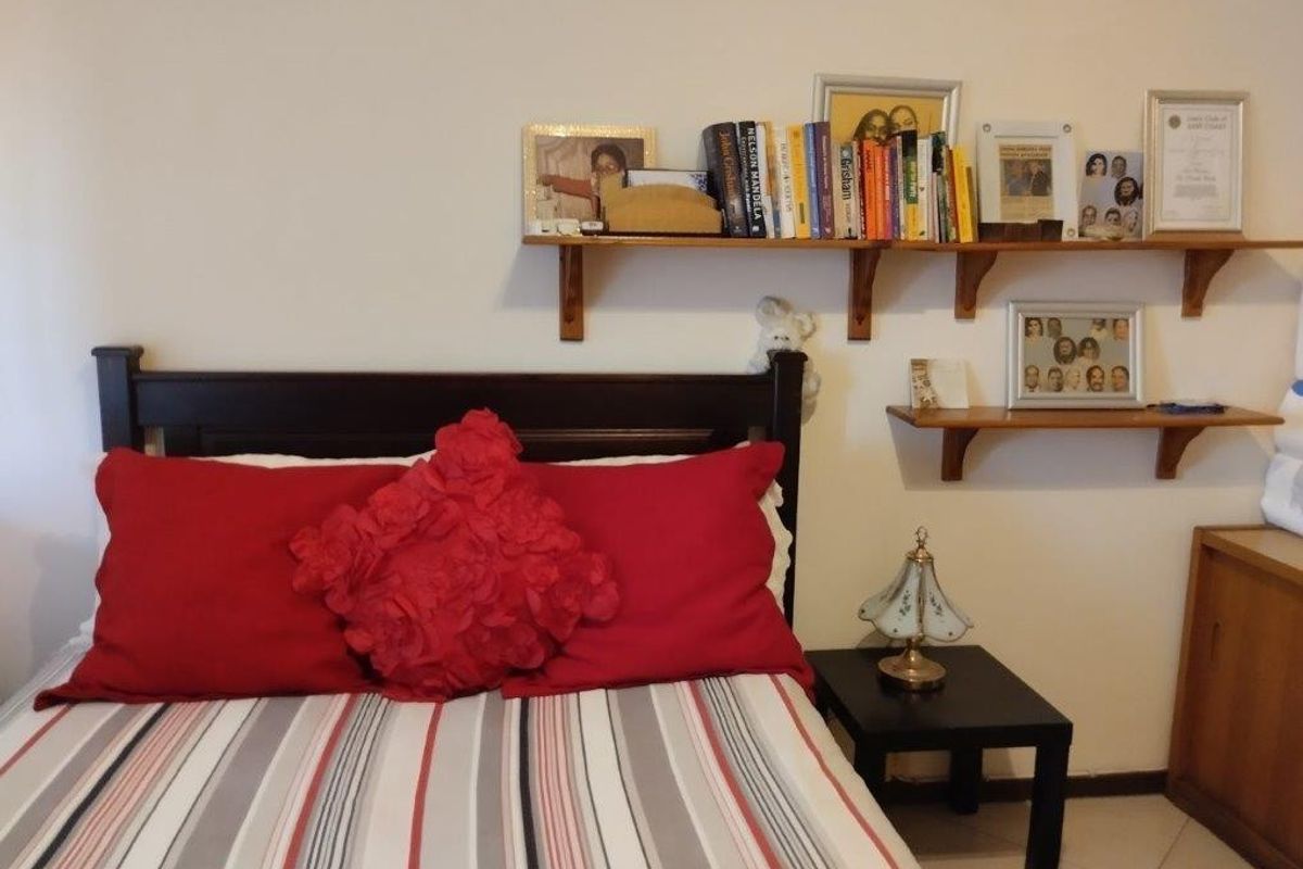 A bedroom featuring wall-mounted shelving units above the bed area.