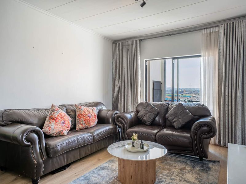 A bright living room featuring laminate flooring and a large sliding glass door that provides natural light and access to the outdoors.