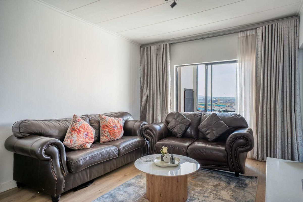 A bright living room featuring laminate flooring and a large sliding glass door that provides natural light and access to the outdoors.