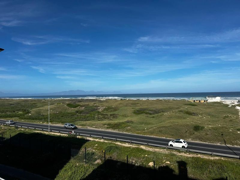 A scenic elevated view overlooking the coastal landscape, road, and ocean horizon.