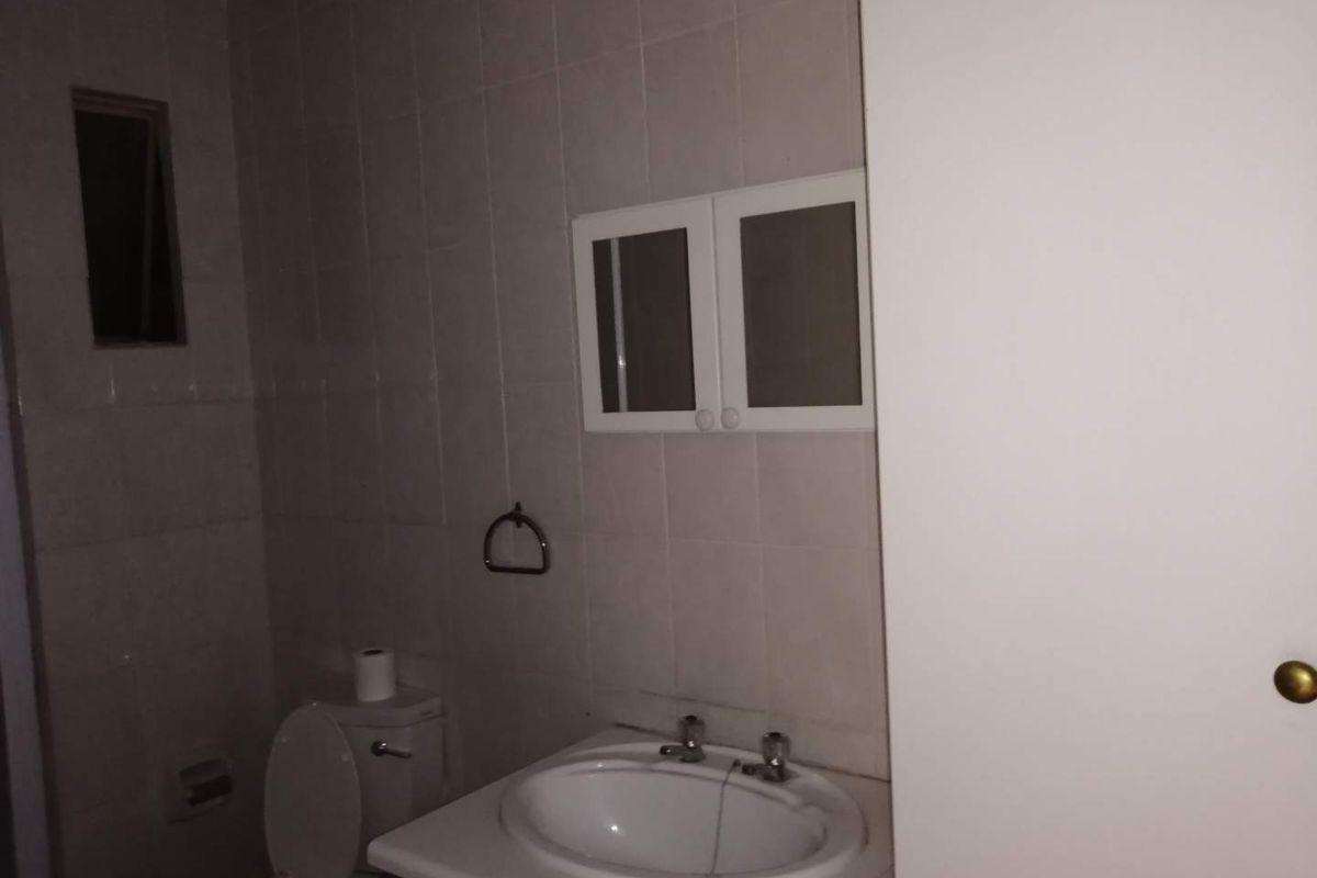 A functional bathroom featuring a vanity with a ceramic basin, wall-mounted medicine cabinet, and tiled walls in a neutral finish.