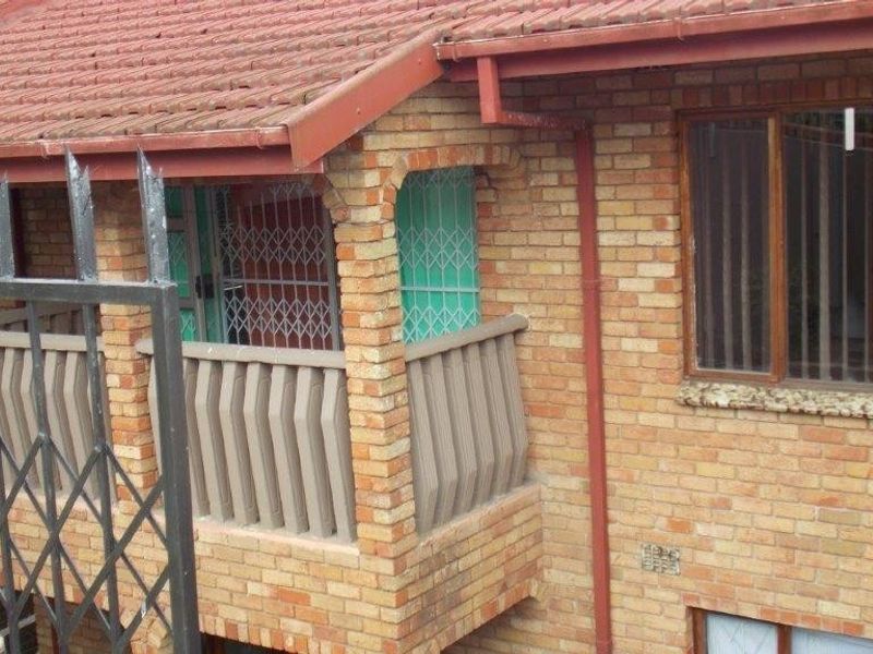 A view of the front facade featuring face brick construction, a tiled roof, and a balcony with integrated security gates and bars.