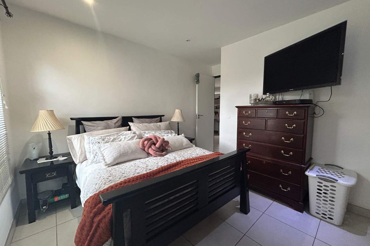 A functional bedroom featuring tiled flooring, recessed ceiling lighting, and a wall-mounted television point.