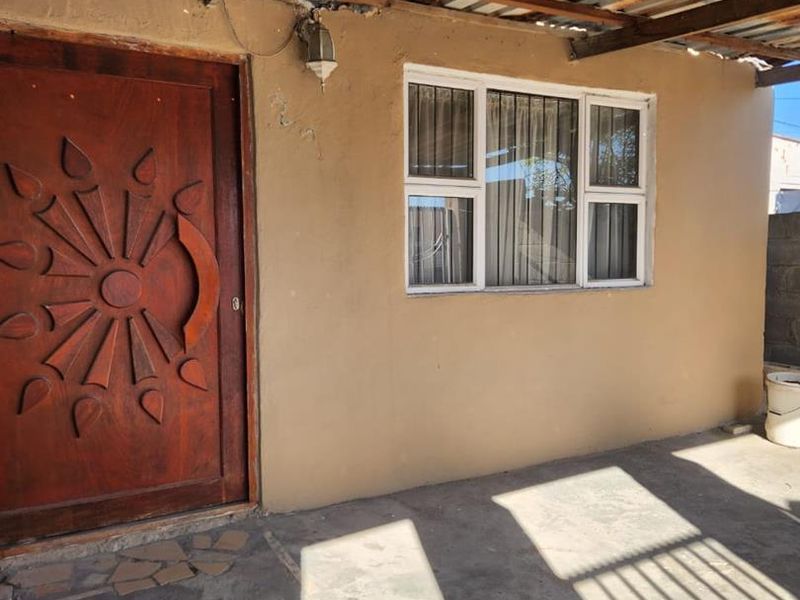 Covered patio area featuring a decorative timber door, aluminium window, and concrete flooring, requiring maintenance to the roof and wall finishes.