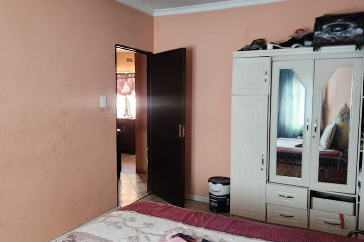 A bedroom featuring peach-toned walls, crown molding, and a doorway leading to an adjacent room.