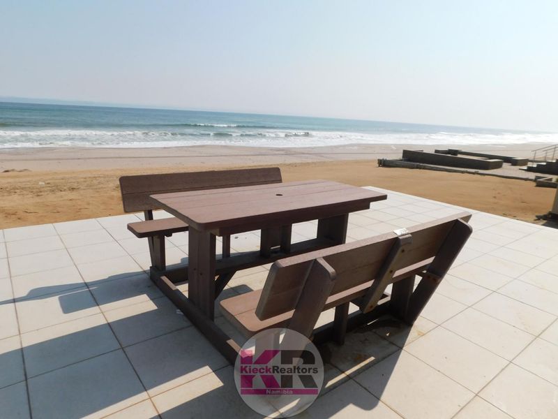 An outdoor tiled patio area situated directly on the beachfront, offering unobstructed ocean views.