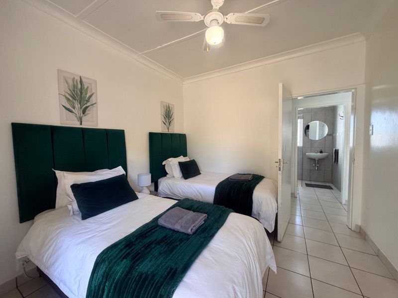 A well-maintained bedroom featuring tiled flooring, a ceiling fan, and direct access to an en-suite bathroom.
