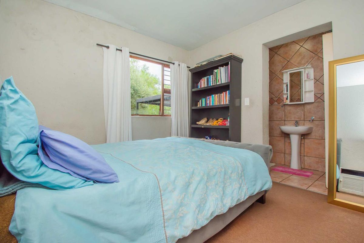 Bedroom featuring an en-suite vanity area with tiled splashback, pedestal basin, and large window providing natural light.