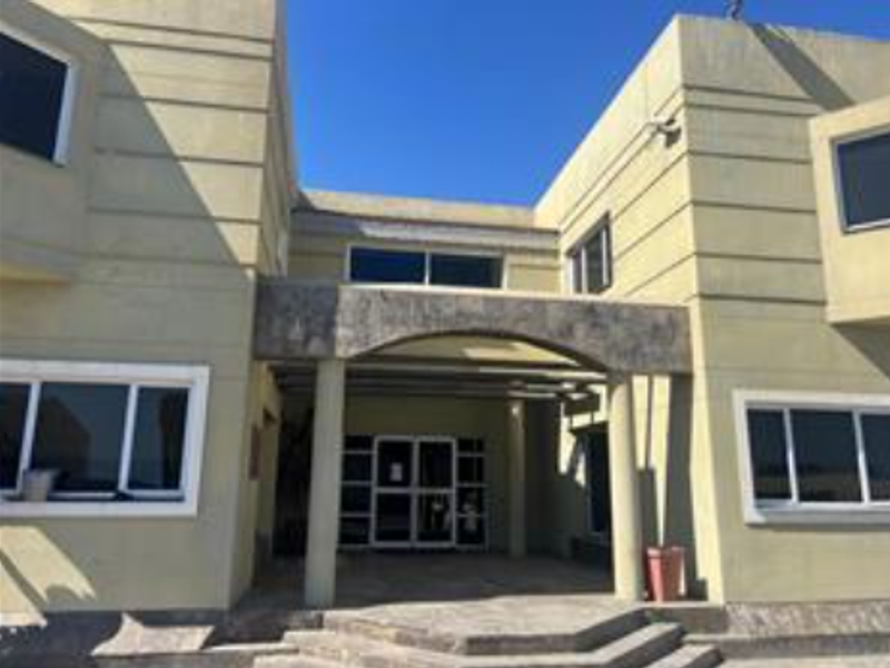 Front elevation of an industrial building featuring a covered entrance with concrete columns and stone steps.