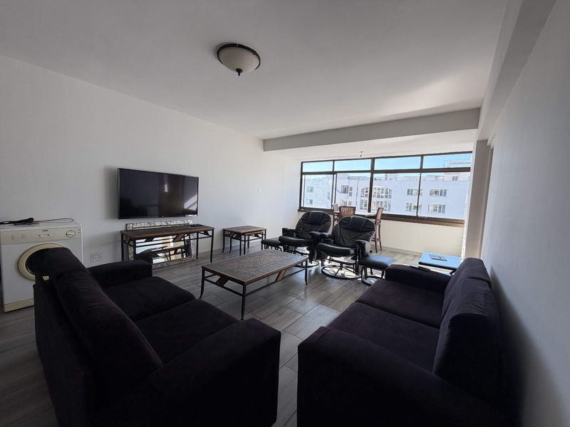 Spacious living room featuring large windows that provide ample natural light and tiled flooring throughout.