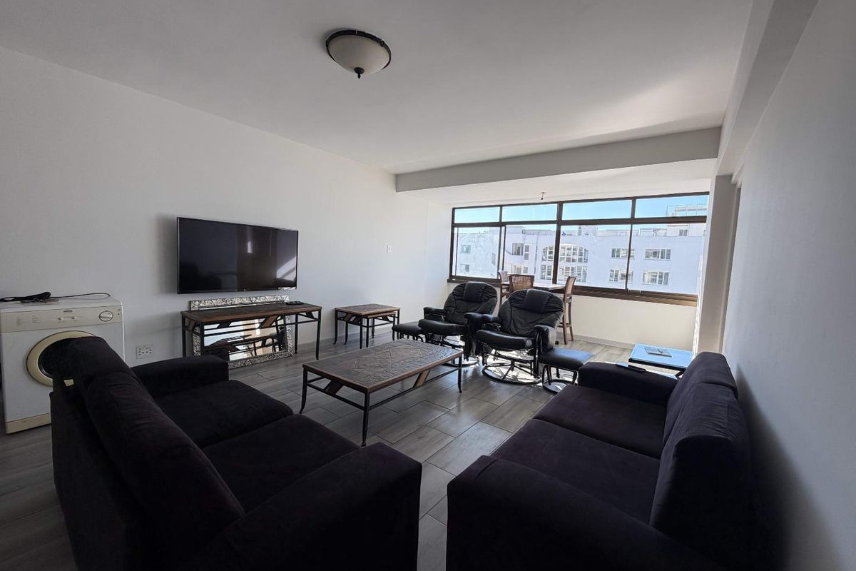 Spacious living room featuring large windows that provide ample natural light and tiled flooring throughout.