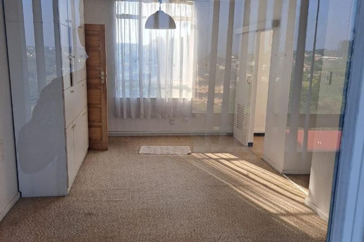 An empty bedroom featuring built-in cupboards, a ceiling fan, and carpet flooring, requiring cosmetic updates to the flooring.