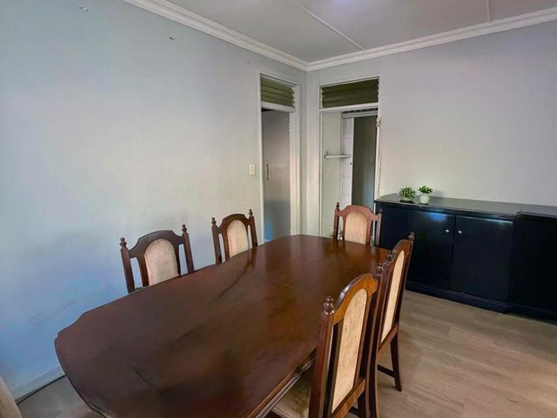 A dining room featuring laminate flooring, crown molding, and a decorative ceiling light fixture.
