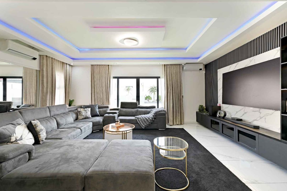 Modern living room featuring a sophisticated recessed ceiling with ambient LED lighting, marble-look feature wall, and integrated media cabinetry.