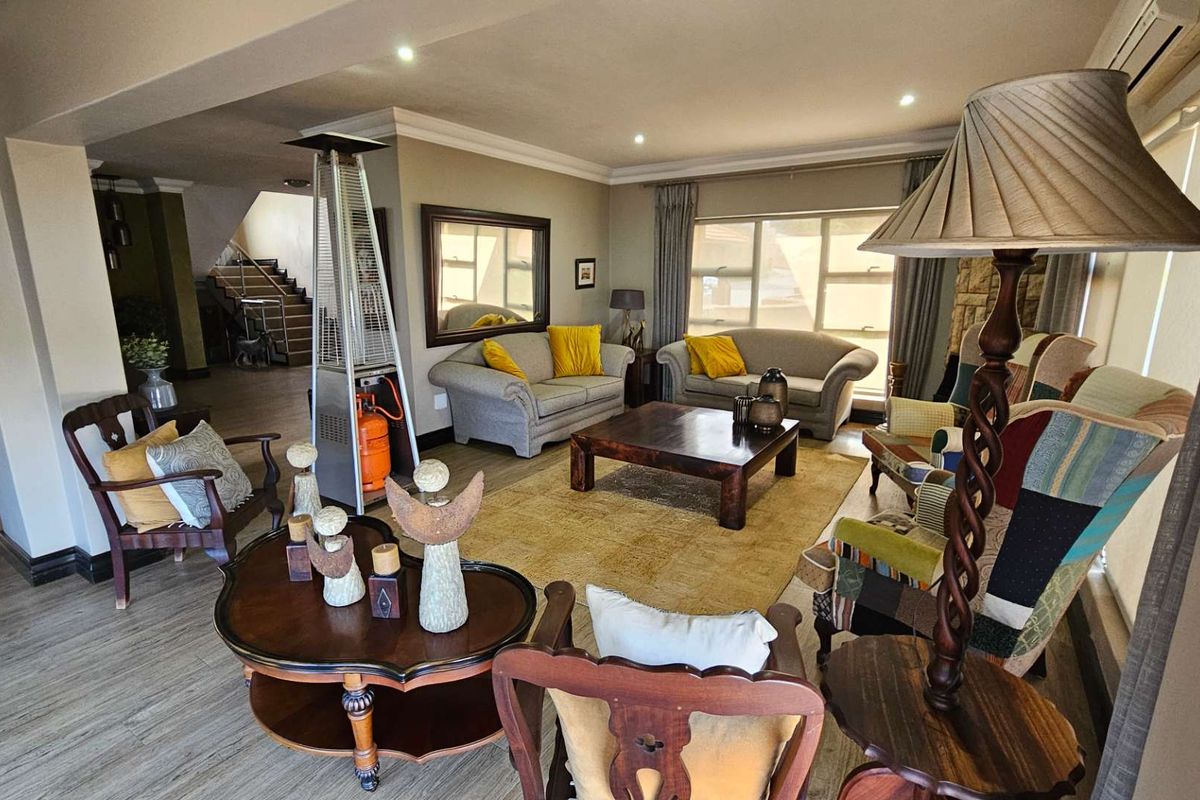 Spacious open-plan living area featuring laminate flooring, recessed downlighting, coved cornicing, and a stone fireplace surround, with an integrated air conditioning unit.
