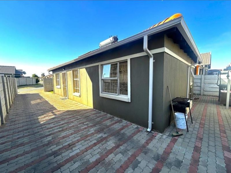 Rear exterior view of the house featuring paved ground, solar geyser installation, and precast concrete boundary walls.