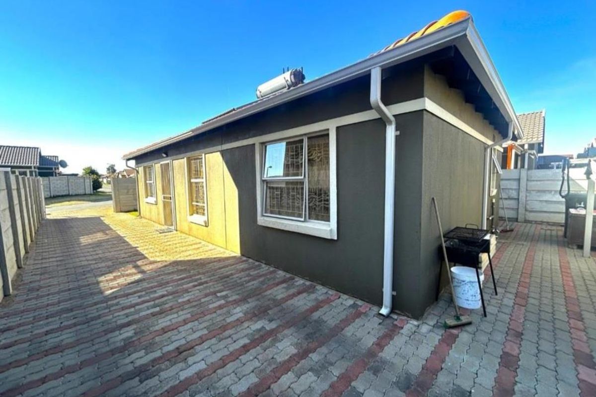 Rear exterior view of the house featuring paved ground, solar geyser installation, and precast concrete boundary walls.