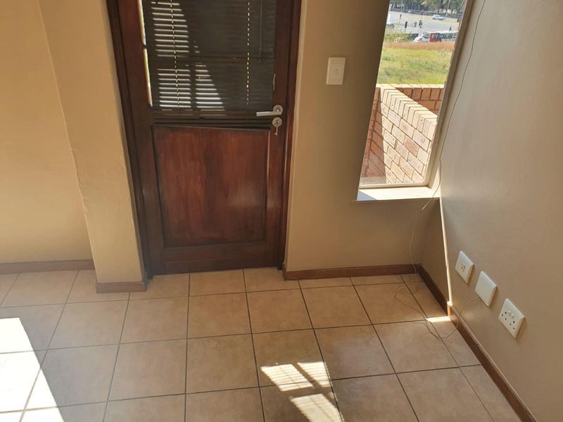 An empty living area featuring tiled flooring, a timber door with integrated blinds, and neutral wall finishes with visible electrical points.