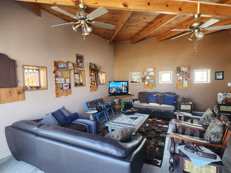 Spacious living area featuring exposed timber ceiling beams, dual ceiling fans, and tiled flooring with a rustic aesthetic.