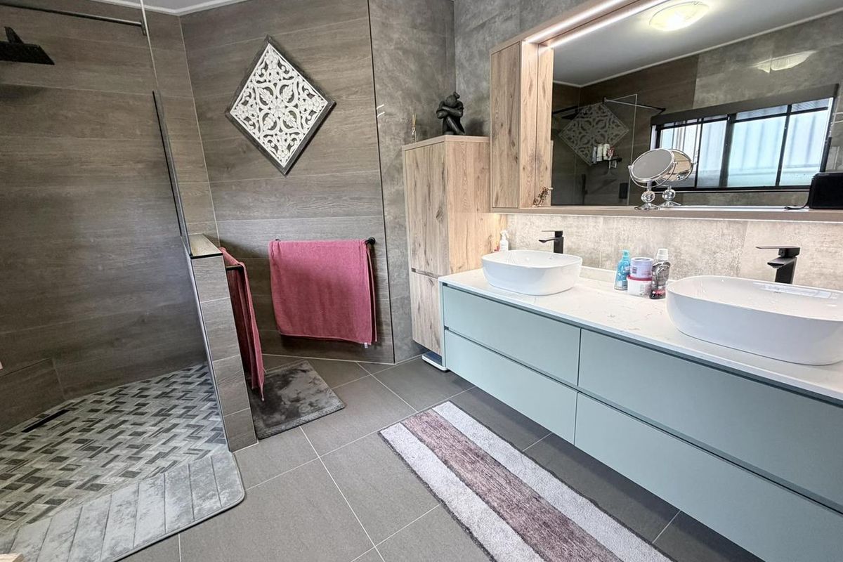 Modern bathroom featuring a spacious walk-in shower with patterned tile flooring, a double vanity with vessel sinks, and integrated LED mirror lighting.