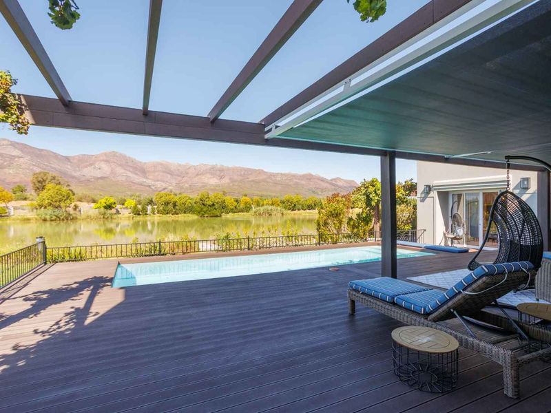 Spacious timber deck featuring a pergola, retractable awning, and swimming pool, offering scenic views of the lake and surrounding mountains.